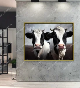 Tableau de deux vaches Holstein noir et blanc en gros plan, avec un cadre doré. Accroché sur un mur moderne en béton ciré gris dans un décor minimaliste.